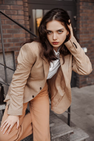 Tall stylish girl with oversized jacket posing near the railing and steps on the city backgroundの写真素材