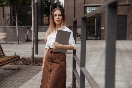 Young business woman holding laptop of the modern office building backgroundの写真素材