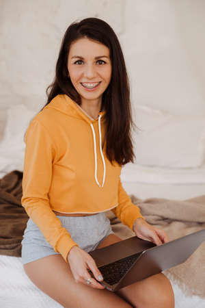 portrait of young freelancer woman using laptop and working at bedroom