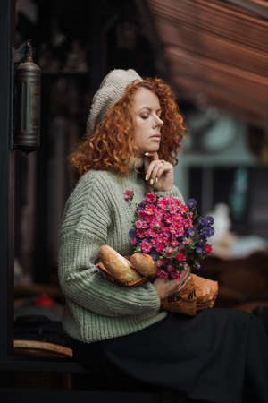 Woman portrait in a beret sweater holding a bouquet of flowers of the restaurant backgroundの写真素材