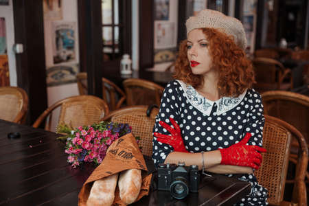 Close up portrait of a woman in a beret and vintage dress at the cafeの写真素材