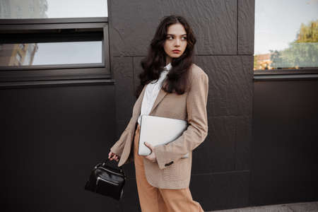 Tall modern girl designer with a laptop in her hands goes to work in the officeの写真素材