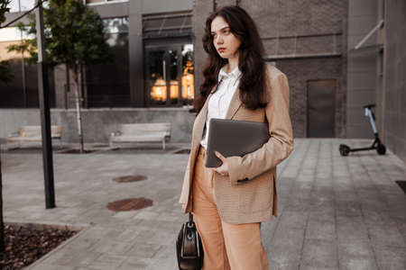 Tall modern girl designer with a laptop in her hands goes to work in the officeの写真素材