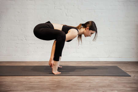 Young woman doing sport exercise Crane or Crow Pose. Bakasana