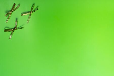 Bright festive lime background with gold bows. Background, texture. Copy space.