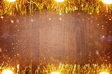 Wooden Christmas background with yellow tinsel around the perimeter. Wooden background with imitation of snow. Background, texture. Copy space.の写真素材
