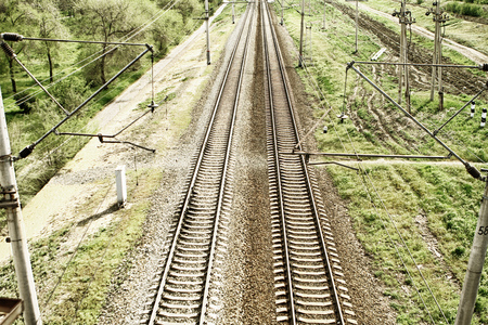 Empty railway tracks in a rural scene with grass and electric linesの写真素材