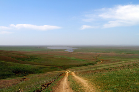 Unpaved dry dirt country road in spring steppe hills, offroad driveの写真素材
