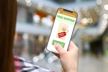 Free shipping concept, girl with frameless phone on blurred mall backgroundの写真素材