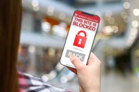 Site blocked concept, girl with frameless phone on blurred mall backgroundの写真素材