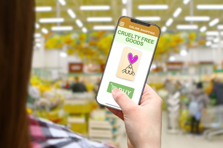 Cruelty free concept, girl with frameless phone on blurred shop backgroundの写真素材