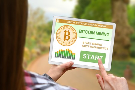 Bitcoin mining concept, girl with tablet pc on blurred nature backgroundの写真素材