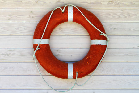 Red lifebuoy on the white wood wall background