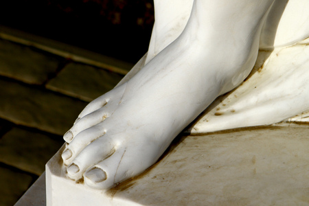 Foot of white beautiful female marble statue close up on dark backgroundの写真素材