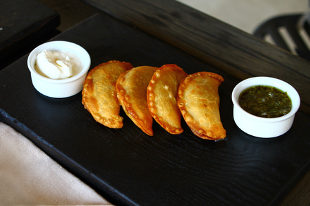 Fried cheburek pies on the dark plate with two saucesの写真素材