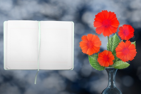 Beautiful live coreopsis bouquet bouquet in ceramic vase on sunny day with opened note book with blank place for your information on park trees and sky blurred background.の写真素材