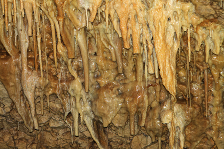 Natural texture image of fantastic natural cave with gingery walls and formations of stalactites...