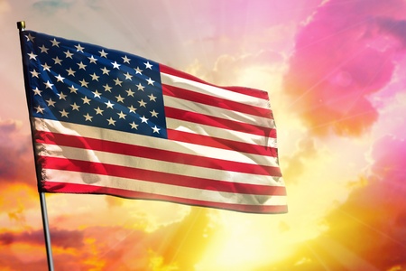 Fluttering USA flag on beautiful colorful sunset or sunrise background. USA success or happiness concept.の写真素材