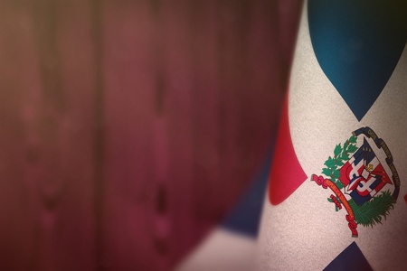 Dominican Republic hanging flag for honour of veterans day or memorial day on pink blurred natural wood wall background. Dominican Republic glory to the heroes of war concept.の写真素材