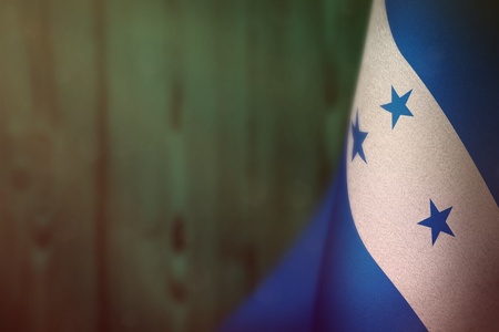 Honduras hanging flag for honour of veterans day or memorial day on teal, sea-green blurred natural wood wall background. Honduras glory to the heroes of war concept.の写真素材