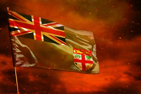 Fluttering Fiji flag on crimson red sky with smoke pillars background. Fiji problems concept.の写真素材