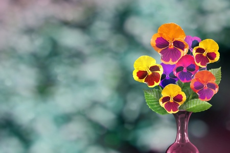 Beautiful live vittrock violets bouquet bouquet in ceramic vase on sunny day with empty space for your content on park trees and sky blurred background.の写真素材
