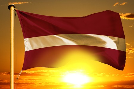 Latvia flag weaving on the beautiful orange sunset backgroundの写真素材