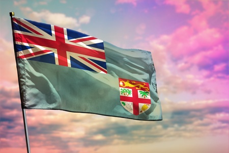 Fluttering Fiji flag on colorful cloudy sky background. Fiji prospering concept.の写真素材