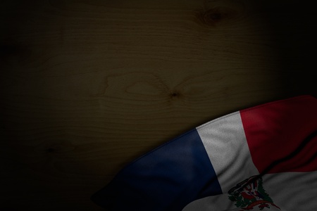 pretty dark photo of Dominican Republic flag with large folds on dark wood with free place for your text - any holiday flag 3d illustrationの写真素材