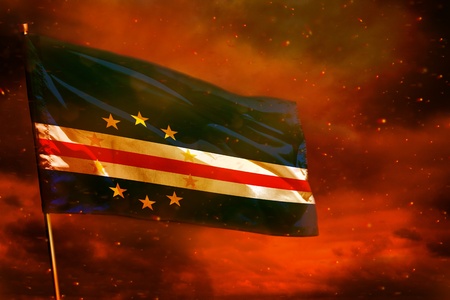 Fluttering Cabo Verde flag on crimson red sky with smoke pillars background. Cabo Verde problems...