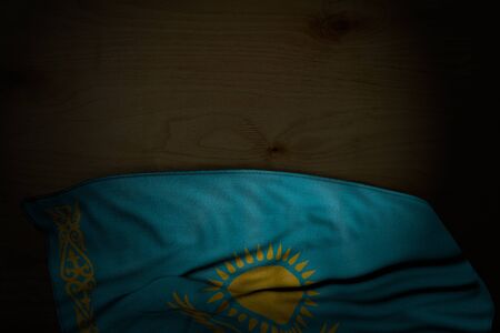 pretty dark picture of Kazakhstan flag with big folds on dark wood with empty place for text - any holiday flag 3d illustrationの写真素材