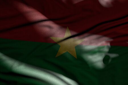 wonderful independence day flag 3d illustration - image of dark Burkina Faso flag with folds lying in shadows with light spots on itの写真素材