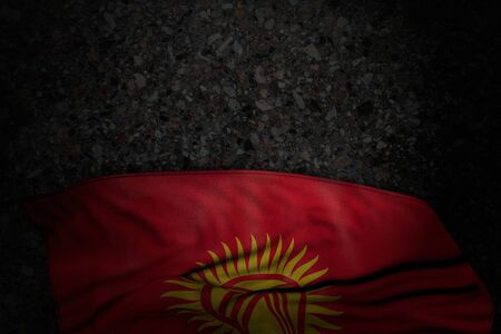 pretty dark image of Kyrgyzstan flag with large folds on dark asphalt with empty place for your content - any holiday flag 3d illustrationの写真素材