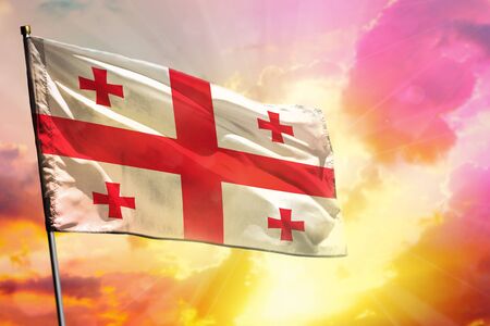 Fluttering Georgia flag on beautiful colorful sunset or sunrise background. Georgia success and happiness concept.の写真素材