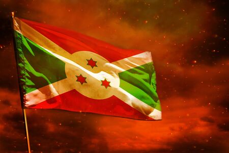 Fluttering Burundi flag on crimson red sky with smoke pillars background. Burundi problems concept.の写真素材