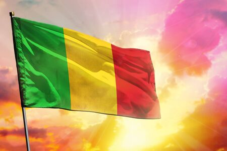 Fluttering Mali flag on beautiful colorful sunset or sunrise background. Mali success and happiness concept.の写真素材