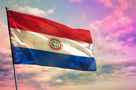 Fluttering Paraguay flag on colorful cloudy sky background. Paraguay prospering concept.の写真素材