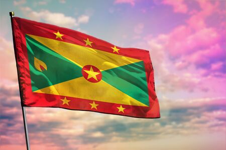 Fluttering Grenada flag on colorful cloudy sky background. Grenada prospering concept.の写真素材