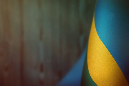 Rwanda hanging flag for honour of veterans day or memorial day on light blue blurred natural wood wall background. Rwanda glory to the heroes of war concept.の写真素材