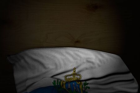 nice dark illustration of San Marino flag with large folds on dark wood with empty place for your content - any feast flag 3d illustrationの写真素材