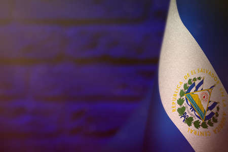 El Salvador hanging flag for honor of veterans day or memorial day on blue blurred painted brick wall background. El Salvador glory to the heroes of war concept.の写真素材