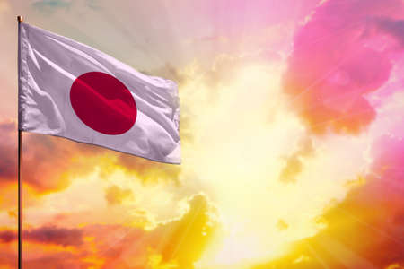 Fluttering Japan flag in left top corner mockup with the place for your information on beautiful colorful sunset or sunrise background.の写真素材