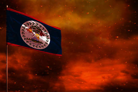 Fluttering Belize flag mockup with blank space for your data on crimson red sky with smoke pillars background. Belize problems concept.の写真素材