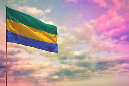 Fluttering Gabon flag mockup with the place for your text on colorful cloudy sky background.の写真素材