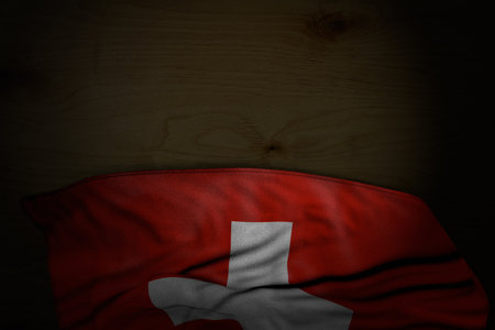 beautiful dark photo of Switzerland flag with large folds on dark wood with free place for your content - any feast flag 3d illustrationの写真素材