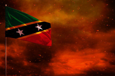 Fluttering Saint Kitts and Nevis flag mockup with blank space for your data on crimson red sky with smoke pillars background. Saint Kitts and Nevis problems concept.の写真素材