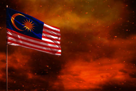 Fluttering Malaysia flag mockup with blank space for your data on crimson red sky with smoke pillars...