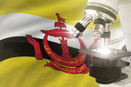 Brunei Darussalam science development concept - microscope on flag background. Research in medicine...
