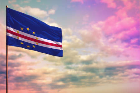 Fluttering Cabo Verde flag mockup with the place for your text on colorful cloudy sky background.
