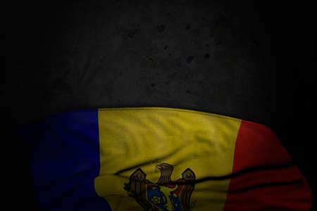 cute dark photo of Moldova flag with big folds on black stone with free space for content - any...